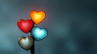Glowing heart shapes in red, orange, blue and silver with luminous effects on soft blurred background, suitable for love and emotion concepts.