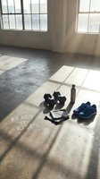 Empty gym space with dumbbells, resistance bands and sneakers on concrete floor with natural window light for fitness motivation and workout preparation.