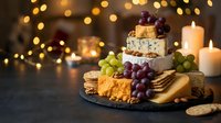 Gourmet cheese platter with crackers, grapes and candles creating warm festive atmosphere for holiday entertaining and wine tasting celebrations.