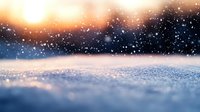 Magical winter landscape with sparkling snow at sunset. Blurred natural background with bokeh effect and falling snowflakes creates dreamy atmosphere.