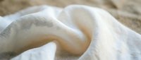 Soft white cotton fabric with gentle folds and natural texture creating elegant drapery for home decor and textile design projects.