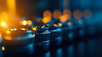 Macro shot of professional audio mixing console faders in dark studio environment with dramatic orange and blue lighting creating atmospheric bokeh effect.