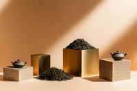Loose black tea leaves scattered and piled on minimal geometric stone and metallic gold pedestals with traditional teapots against warm beige background. Modern tea concept.
