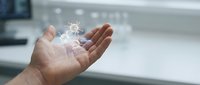 Hand holding glowing digital network connections with light particles floating above palm in modern office environment for technology concepts.