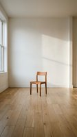 Minimalist wooden chair in empty room with natural light casting shadows on white walls and hardwood floors for interior design concepts.