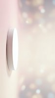 Elegant white feather floating on soft pink bokeh background with dreamy light effects for wellness and spiritual design projects.