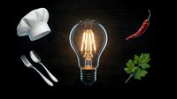 Culinary creativity concept with glowing vintage lightbulb surrounded by chef hat, utensils, chili pepper and herbs on dark wooden background for restaurant branding.