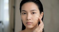 Young Asian woman testing foundation shades on cheek, beauty routine concept, skincare and makeup application for flawless complexion.
