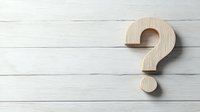 Wooden question mark symbol on white rustic wooden planks background with copy space. Minimalist concept for questions, FAQ, and problem solving.
