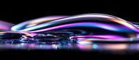 Colorful iridescent soap bubble macro with vibrant rainbow reflections on dark background showing delicate surface tension and light refraction patterns.