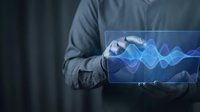 Businessman holding futuristic holographic tablet displaying blue digital wave pattern for technology presentations and data visualization concepts.