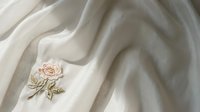 Embroidered rose flower on cream linen fabric with soft folds, suitable for textile design, fashion, and home decor projects.