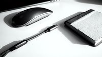 Modern minimalist workspace with wireless mouse, notebook and pen on clean white desk for productivity and business planning.