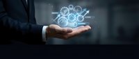 Businessman holding glowing digital cloud computing network with gears and data connections floating above palm in modern office environment.