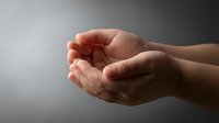 Cupped hands in protective gesture against soft gray background symbolizing care, support, protection, and offering help in gentle lighting.