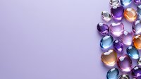 Colorful heart-shaped glass beads scattered on purple background creating romantic border composition with copy space for valentines design projects.