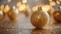 Golden Christmas ball with star pattern on glittery surface against blurred warm bokeh background creates festive holiday atmosphere.