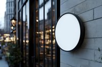 Blank circular signage on modern storefront exterior with urban street view and evening lighting for branding and retail mockups.