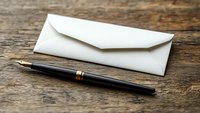 White envelope and luxury fountain pen on rustic wooden table surface. Business correspondence and traditional writing concept for formal communication.