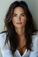 Young woman with long dark hair wearing white shirt, natural makeup and confident expression against light background. For beauty, fashion and lifestyle content.