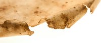 Aged paper texture with torn edges and brown stains, suitable for vintage backgrounds, scrapbooking, and antique design projects.
