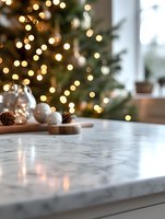 Marble countertop with festive decorations and blurred Christmas tree lights creating magical bokeh effect in background, cozy holiday home atmosphere.