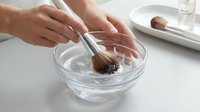 Woman mixing homemade face mask with brush in glass bowl for natural skincare routine and beauty treatment at home spa.