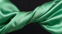 Twisted green satin ribbon with gold stitching detail on black background, suitable for luxury branding, gift wrapping design, and premium packaging projects.