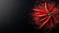Fresh red chili peppers arranged in star shape with scattered red chili flakes on black background, dramatic food photography for restaurant menu design.