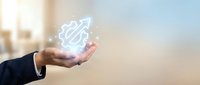 Businessman hand holding glowing digital brain network symbol representing artificial intelligence and machine learning technology in modern office.