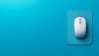 White wireless computer mouse on blue mousepad against turquoise background with copy space, minimalist office technology concept for business and remote work.