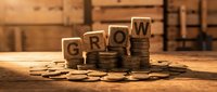 Wooden letter blocks spelling GROW stacked on increasing coin piles representing financial growth and investment success on rustic wooden background.