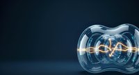 Glowing filament inside transparent glass bulb on dark blue background, representing energy, innovation, and technology concepts for business and science applications.