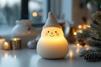 Adorable glowing snowman figurine with warm LED light creates cozy winter atmosphere among pine branches and bokeh lights for holiday home decor and seasonal celebrations.