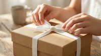 Hands unwrapping kraft paper gift box with white ribbon, perfect for e-commerce, retail, holiday marketing, and packaging design projects.