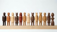 Wooden carved figurines in various natural tones standing in a row on a wooden base, representing diverse characters for decorative or educational purposes.