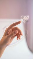 Hand reaching toward floating heart icon in soft pink purple gradient background for digital love romance technology interface design.