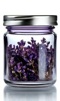 Dried lavender flowers stored in clear glass jar with metal lid, isolated on white background for herbal tea, aromatherapy, and craft projects.