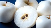 Fresh white Korean pears with one sliced in half showing juicy flesh and seeds on blue background, perfect for healthy eating and culinary concepts.
