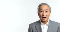 Senior Asian male professional in gray blazer and white shirt against white background, suitable for corporate, business, and editorial use.