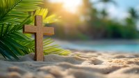 Wooden cross on tropical beach sand with palm leaves and golden sunlight creating peaceful spiritual atmosphere for meditation and faith concepts.