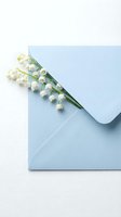 Delicate lily of the valley flowers emerging from light blue envelope on white background for spring greeting cards and wedding invitations.