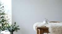 Cozy bedroom corner with wooden nightstand, fluffy white blanket, vintage alarm clock, and fresh green plant decoration for home interior design and lifestyle content.