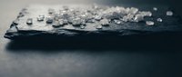 Water droplets on dark slate stone surface creating natural texture and moisture pattern for spa wellness and nature concepts.