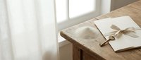 Blank envelope and letter tied with twine on wooden desk near window with natural light, suitable for stationery and correspondence designs.