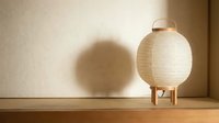 Cream paper lantern lamp with wooden legs casting shadow on beige wall, modern minimalist home decor and lighting design element.