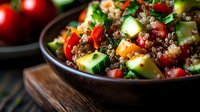 Fresh quinoa salad with colorful vegetables, cucumber, tomatoes, and pomegranate seeds in wooden bowl on rustic background. Healthy vegan meal rich in protein.