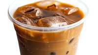 Refreshing iced coffee drink with milk in plastic cup, brown creamy beverage with ice cubes floating on top, close up view against white background.