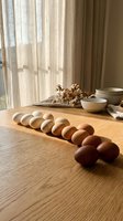 Fresh brown eggs arranged on wooden table in warm sunlight with ceramic bowls and dried flowers creating cozy kitchen atmosphere for cooking and baking.