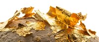Gold leaf and flakes scattered on textured stone surface, isolated on white background. Suitable for luxury branding, design projects, and decorative applications.
